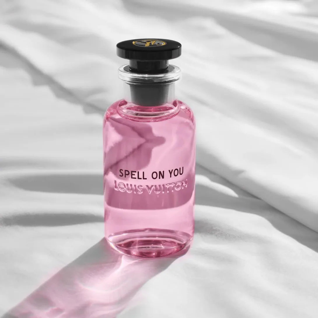Pink perfume bottle labeled 'Spell on You' by Louis Vuitton on a white fabric background